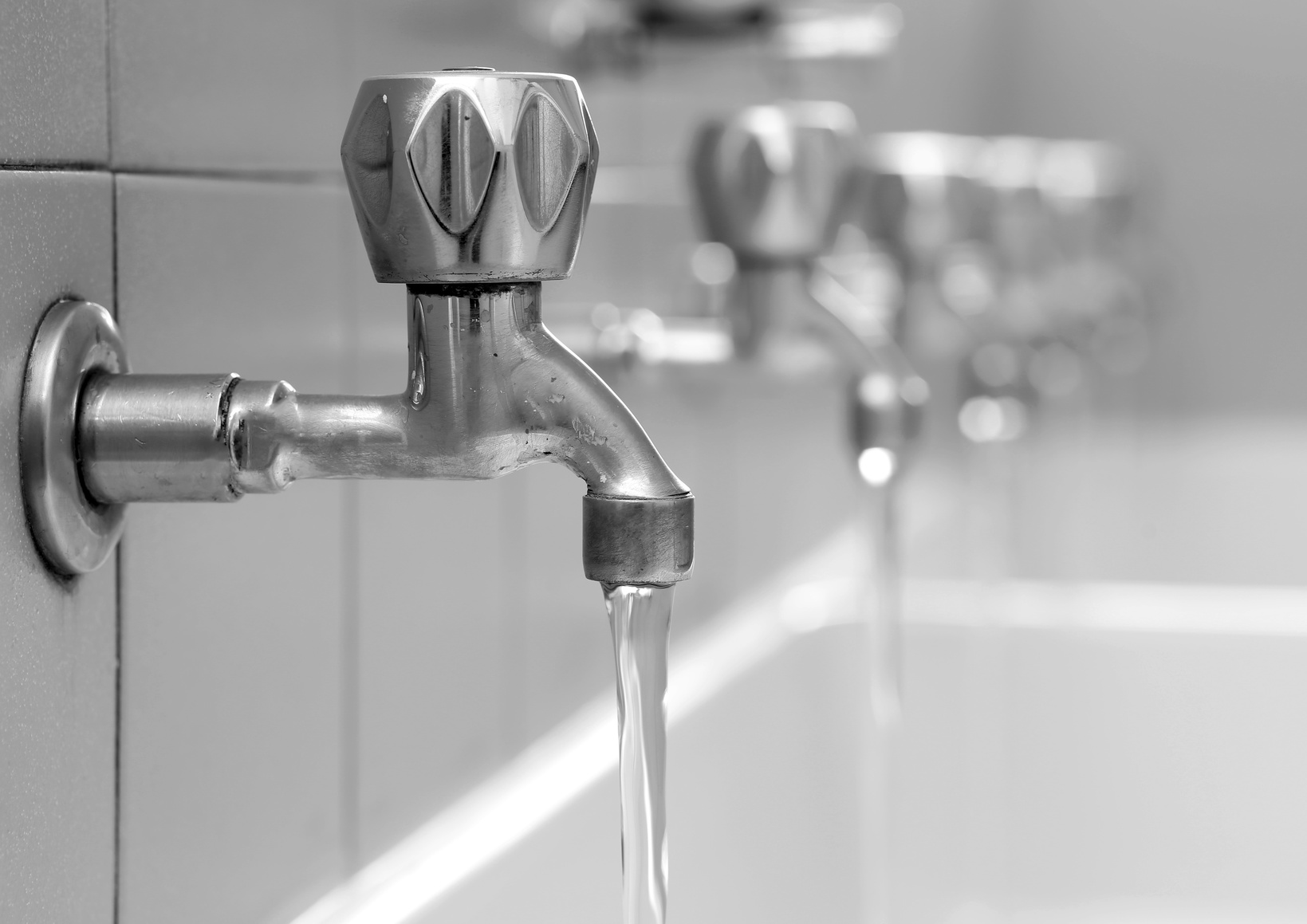 steel open faucets with water flowing in the bath changing rooms